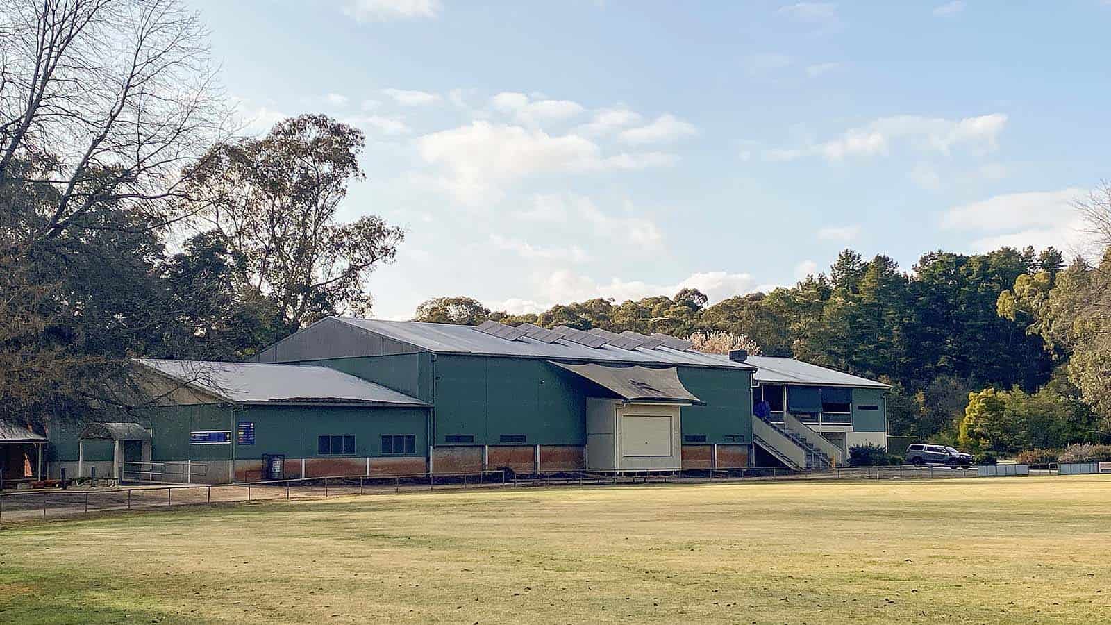 Photo of a Colorbond clad recreational building, with a smaller annex on either end, with a grassed area in front of it